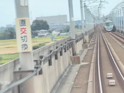 電車内から進行方向の線路を見ています。線路の脇の電柱には「直交切替」という看板があります